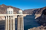 Detailed view of the Hoover Dam intake towers standing above the Colorado River, showing water levels and surrounding rocky desert terrain