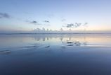 Ocean reflection of dusk sky on the beach. 
