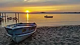 Sunset at Gull Lake, Minnesota, with row boat pulled onto sandy beach.