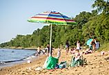 A beach umbrella stands in the sand at Matapeake Clubhouse and Beach on Kent Island, Maryland. Image credit Nicole Glass Photography via Shutterstock. 