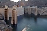 Detailed view of the Hoover Dam intake towers standing above the Colorado River, showing water levels and surrounding rocky desert terrain