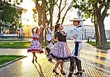 At sunset in La Serena, Chile, two Latin American couples dressed as huasos dance cueca in the town square.