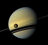 Titan in front of the ring and Saturn (Produced By: Cassini Imaging Team, Image Credit: NASA/JPL-Caltech/Space Science Institute, Public domain, via Wikimedia Commons)