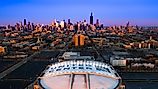 Beautiful Aerial View of Iconic United Center Stadium with Chicago Skyline in Background at Blue Hour. 