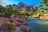 Visitors sitting by the Virgin River in Utah's Zion National Park.