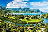 A vibrant aerial view of the lush landscape of Hanalei Bay, framed by majestic mountains under a sunny, blue sky in Kauai, Hawaii.