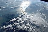 A stunning view of Earth from space, showcasing the vastness of the ocean and the intricate patterns of clouds illuminated by the sun.