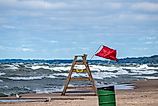 Red warning flag flying on a wooden lifeguard chair at Lake Michigan during hazardous water conditions