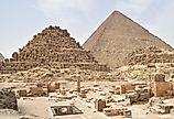 Pyramids of Giza complex in Cairo, Egypt, with Menkaure, Khafre, and Khufu pyramids under clear desert sky.