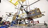 Dragonfly suspended by bungee cords during its ground vibration testing. By NASA/Johns Hopkins APL/Ed Whitman - https://science.nasa.gov/blogs/dragonfly/2026/07/09/nasas-dragonfly-clears-key-tests-as-titan-rotorcraft-takes-shape/, Public Domain, Wikimedia