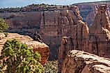 A hiker is sitting on a cliff in the Colorado National Monument area in Colorado.