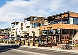 Tourists and locals enjoy a drink on the trendy sidewalk bar and restaurants in Wanaka lakefront in Wanaka, New Zealand. Editorial credit: AsiaTravel / Shutterstock.com