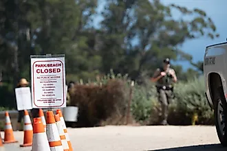 Closed regulation sign posted beside orange cones at a trail access point.