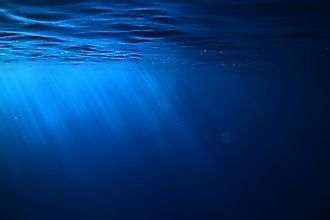 Underwater view of the ocean with rays of sunlight filtering through blue water