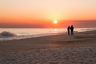 A loving couple take a stroll at sunset along the beach at Navarre Beach, Florida.