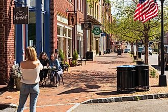 A slender blonde woman's back faces the camera as she photographs two friends at a sidewalk table outside 'Downtown Sweet' in Jonesborough, TN. Editorial credit: Nolichuckyjake / Shutterstock.com