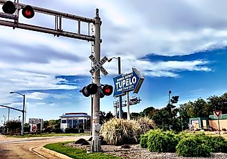 Business District sign and railroad crossing in Tupelo, Mississipi. Via Shutterstock / Lucideye-James Walker.