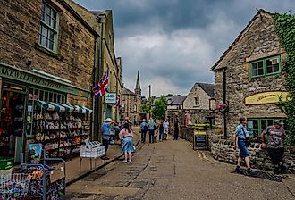 Stone shopfronts and pedestrians line a narrow street in Bakewell, Derbyshire. Editorial credit: Emad Aljumah / Shutterstock.com