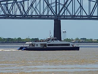 A ferry crosses the Mississippi River under a bridge in New Orleans, via Wirestock on iStock.com