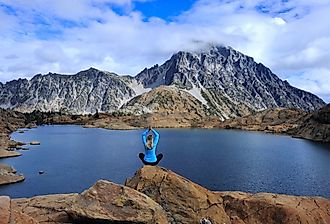 Woman doing a yoga post on a rock overlooking Ingalls Lake, WA.
