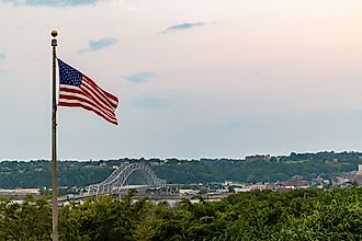 A view of the American flag and Julien Dubuque Bridge against blue sky at sunset in Dubuque city, Iowa, United States