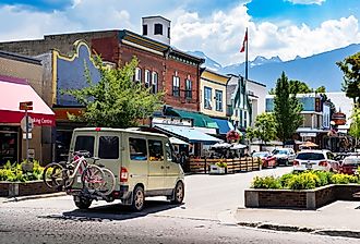 A camperized van with mountain bikes drives down the Main Street, with Selkirk Mountains in Revelstoke, British Columbia. Image credit Ramon Cliff via Shutterstock 