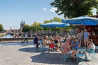 People enjoying outdoor terraces along the harbor in the historic city of Zierikzee, Netherlands. Editorial credit: Wolf-photography / Shutterstock.com