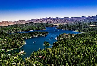 Aerial, drone panorama of Lake Arrowhead in the San Bernardino Mountains, California on a clear, summer day with blue water and sky, purple mountains and green trees