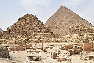 Pyramids of Giza complex in Cairo, Egypt, with Menkaure, Khafre, and Khufu pyramids under clear desert sky.
