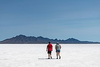 Two people walking on the white salt pan of the Bonneville Salt Flats a remnant of the Pleistocene Lake Bonneville. 