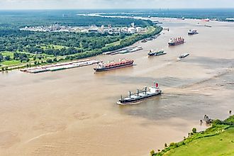 A variety of different cargo ships sailing along the Mississippi River near New Orleans