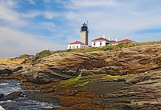 Editorial Photo Credit:Stephen B. Goodwin via Shutterstock. The Beavertail Light lighthouse near Jamestown on Conanicut Island, Rhode Island, viewed from the rocky coast with a bright blue sky and white clouds