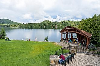Tourists on lawn in front of Mirror Lake in Lake Placid, New York. Image credit: Catrina Genovese / Shutterstock.com.