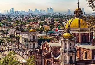 Mexico. Basilica of Our Lady of Guadalupe. Cupolas of the old basilica and cityscape of Mexico City. Image credit WitR via Shutterstock
