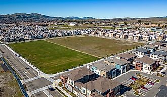 Aerial photos over apartments and houses in Dublin, California with a green field and solar panels