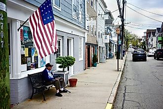 An elderly man seated under an old American flag on Main Street in Stonington, Connecticut. Editorial credit: Joe Tabacca / Shutterstock.com