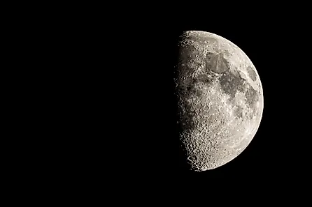 The first quarter moon reveals a hint of its "dark side."  Via Shutterstock / Jordon Sharp