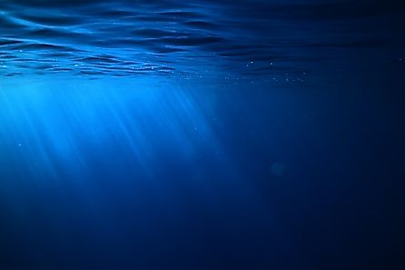 Underwater view of the ocean with rays of sunlight filtering through blue water