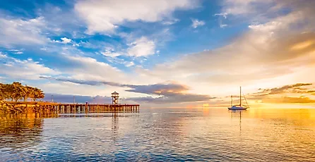 A boat anchored on the calm waters of the Puget Sound as the early morning sun rays warm the cloud ridden sky at Port Angeles, Washington.