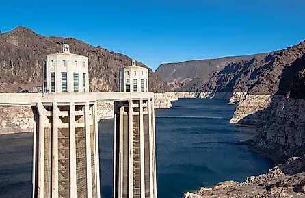 Detailed view of the Hoover Dam intake towers standing above the Colorado River, showing water levels and surrounding rocky desert terrain