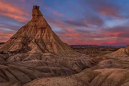 A stunning view of a unique rock formation in Bardenas Reales, Spain, under a vibrant sunset sky