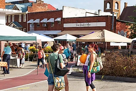 JONESBOROUGH, TN, USA-9/29/18: 3 women talk, while one holds a large pumpkin at Farmers' Market.