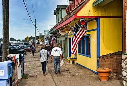People walking on a sidewalk in front of shops in downtown Depoe Bay, Oregon. Image credit Bob Pool via Shutterstock