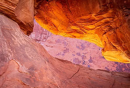Petroglyphs on the dramatic red sandstone formation of Atlatl Rock with natural arch in Valley of Fire State Park Nevada.