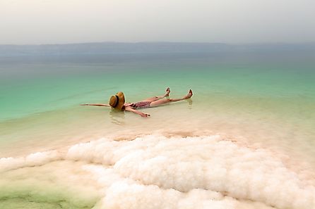 Woman relaxing in salty water of the Dead Sea. Via Shutterstock / xamnesiacx84