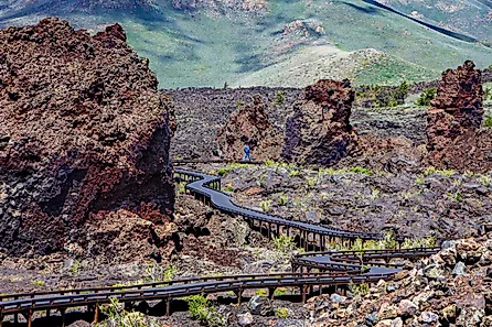 A visitor walks along the snaking boardwalk along the North Crater Flow Trail, Craters of the Moon National Monument, ID