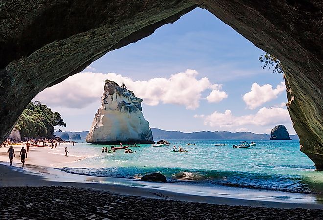 Cathedral Cove, beautiful beach with rocks and tourists in cave in Hahei, New Zealand. Image credit riekephotos via Shutterstock.com