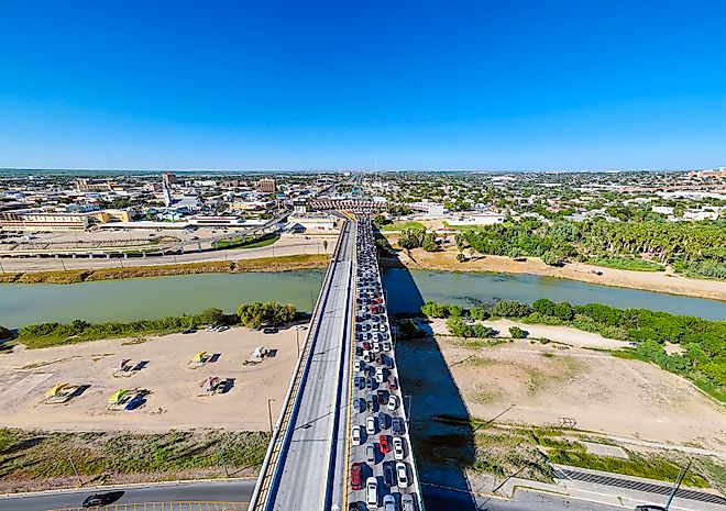 High-angle drone photograph capturing a dense queue of northbound vehicles stretching across the Juarez-Lincoln International Bridge over the Rio Grande. 