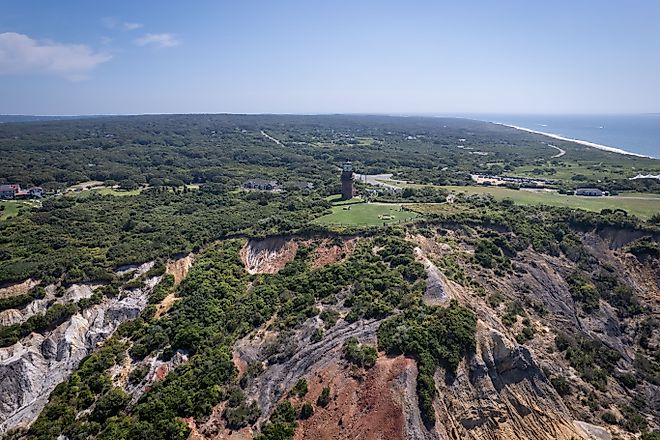 Aerial of scenic cliffs and lighthouse at Gay Head in Martha's Vineyard, with lush greenery and ocean views.