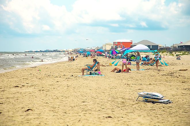People enjoying a a busy summer beach day in Dauphin Island, Alabama. Image credit: HarrisonJeffs / Shutterstock.com